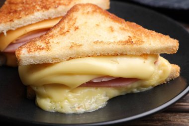 Eritilmiş peynirli ve ahşap masada jambonlu lezzetli sandviçler.