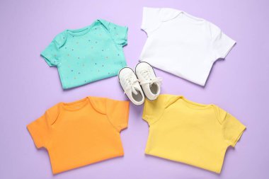 Mor arka planda şık bebek kıyafetleri ve ayakkabıları var.