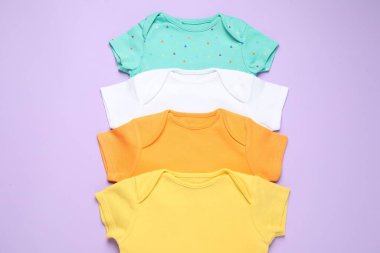 Mor arka planda şık bebek kıyafetleri, düz yatış