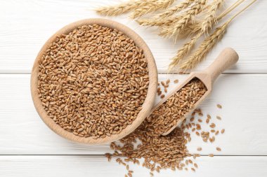 Kasede buğday taneleri, beyaz ahşap masada kepçeler ve çiviler, düz uzanmış