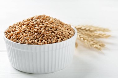 Kasede buğday taneleri, beyaz ahşap masada çiviler, yakın plan. Metin için boşluk