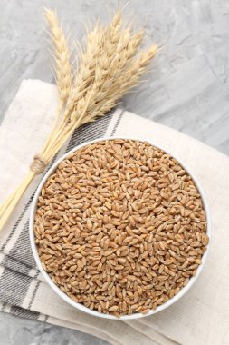 Kasede buğday taneleri ve gri masada sivri uçlu çiviler.