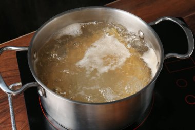 Taze tagliatelle makarnası tencerede kaynar su ve elektrikli soba, yakın plan.