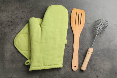 Yeşil fırın eldiveni ve diğer mutfak gereçleri koyu dokulu masa, düz yatıyordu.