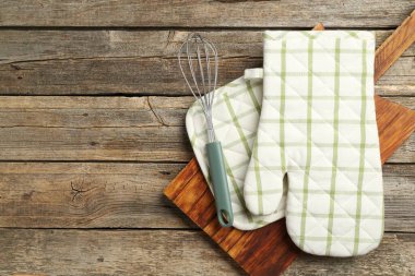 Fırın eldiveni ve diğer mutfak gereçleri ahşap masada, üst tarafta. Metin için boşluk