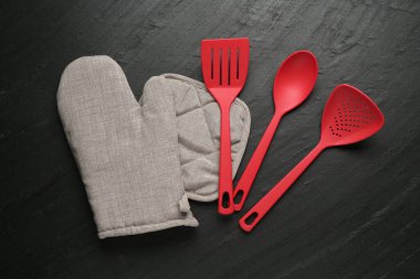 Gri fırın eldiveni ve diğer mutfak gereçleri koyu dokulu masa üzerinde, düz yatıyordu.