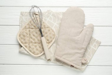 Fırın eldiveni, tutucu, çırpıcı ve havlu beyaz ahşap masa, düz uzanma