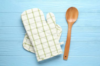 Fırın eldiveni, tutucu ve kaşık açık mavi ahşap arka planda, düz yatıyordu.