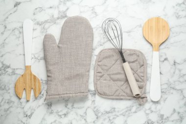 Fırın eldiveni, tutkal ve diğer mutfak gereçleri beyaz mermer masa, düz yatıyordu.