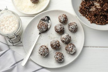 Fındıklı çikolatalı şekerler, hindistan cevizli gevrekler ve beyaz ahşap masada pilav.