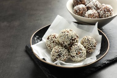 Fındıklı çikolata şekerlemeleri, susam tohumları ve gri masada hindistan cevizi taneleri, yakın plan.