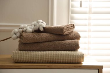 Temiz havlular ve pamuk çiçekleri evdeki ahşap çekmecelerin üzerinde, yakın plan.