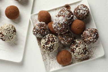 Beyaz masa üzerinde kakao tozu, fındık ve susam tohumlu lezzetli çikolata şekerlemeleri.