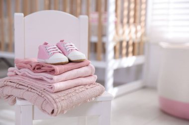 Temiz bebek kıyafetleri, ayakkabılar ve aksesuarlar kapalı bir sandalyede, yakın plan. Metin için boşluk