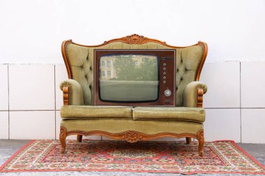 Dışarıdaki beyaz duvarın yanında kanepe ve halı üzerinde Retro TV. Kullanılmış eşyalar