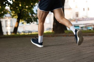 Spor giyimli atletik genç adam dışarı koşuyor, yakın plan.