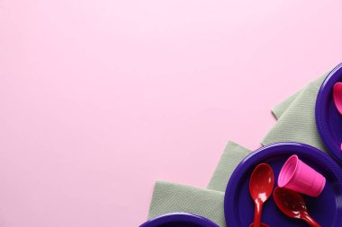 Pembe arka planda tek kullanımlık plastik sofra takımı ve kağıt peçeteler. Metin için boşluk
