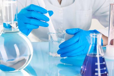 Laboratuvarda, beyaz masada nitrat testi yapan bilim adamı, suyu yakından inceliyor.