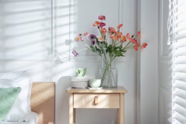 Yatağın yanında farklı dekorları olan bir komodin.