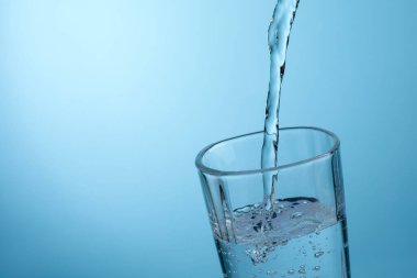 Açık mavi gradyan arkaplana karşı ferahlatıcı soda bardağına dökülüyor, yakın plan. Metin için boşluk