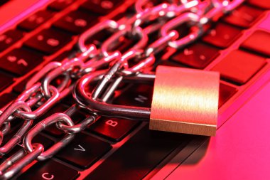 Siber güvenlik. Metal asma kilit, dizüstü bilgisayarında renk ışığı, yakın plan.