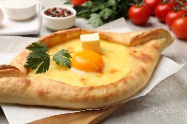 Peynirli, yumurtalı, maydanozlu ve açık gri arkaplanlı diğer ürünlerle lezzetli khachapuri, yakın plan.