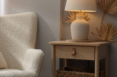 Şık ahşap sehpa. Evdeki koltuğun yanında lamba var. Yakın plan.