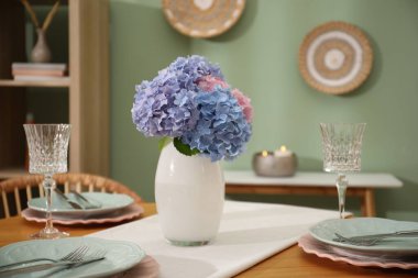 Yemek odasındaki ahşap masada tabaklar ve vazolarla şık bir ortam, yakın plan. İç tasarım