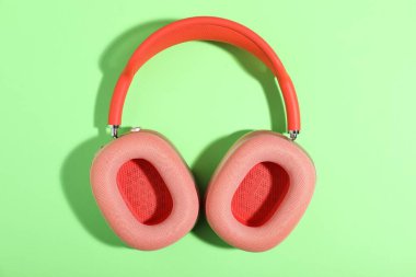 Açık yeşil arka planda bir çift şık pembe kulaklık.