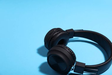 Açık mavi arka planda bir çift şık kulaklık, yakın plan. Metin için boşluk