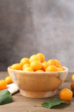 Olgun sarı kiraz erikleri ve ahşap masanın üzerindeki yapraklar. Metin için boşluk