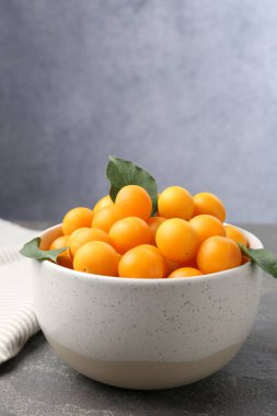 Gri masada olgun sarı kiraz erikleri ve yaprakları. Metin için boşluk