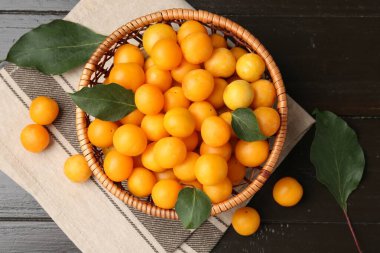 Olgun sarı kiraz erikleri ve koyu ahşap masa üzerinde yapraklar, düz uzanmış