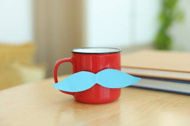 Babalar Günün kutlu olsun. Bıyıklı kupa ve defterler kapalı masa üzerinde.