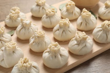 Ahşap masada pişmemiş khinkaliler (hamur tatlısı), yakın plan.