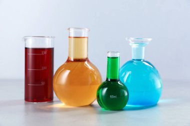 Işık arka planında renk sıvıları olan farklı laboratuvar camları.