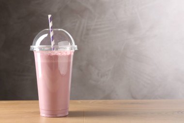 Tahta masada plastik bardakta lezzetli milkshake, metin için yer.