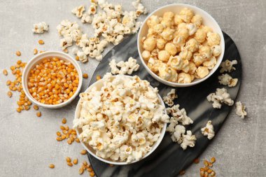 Açık gri masada patlamış mısır ve mısır taneleri, düz uzanmış