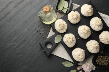 Biber, sarımsak ve defne yapraklarıyla pişirilmemiş khinkaliler (hamur köfteleri) siyah masada, düz yerde. Metin için boşluk