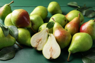 Taze olgun armutlar ve yeşil ahşap masada yapraklar, yakın plan.
