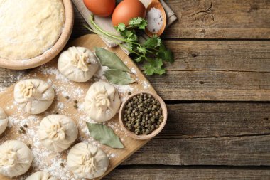 Biber, un ve defne yapraklarıyla ahşap masa üzerinde pişmemiş khinkaliler (hamur köfteleri). Metin için boşluk