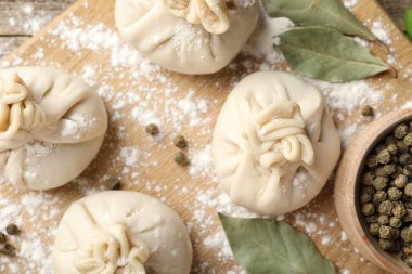 Biber, un ve defne yapraklarıyla pişirilmemiş khinkaliler (hamur köfteleri) ahşap masada, düz yatıyordu.