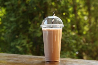 Dışarıdaki ahşap masada plastik bardakta lezzetli bir milkshake.