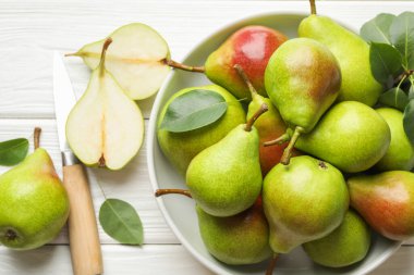 Taze armutlar, bıçak ve yeşil yapraklar beyaz ahşap masada, düz yatıyordu.