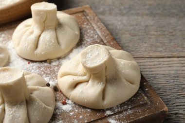 Ahşap masada pişmemiş khinkaliler (hamur tatlısı), yakın plan.