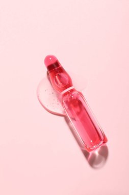 Pembe zemin üzerinde sıvı olan cam ampul, üst görünüm