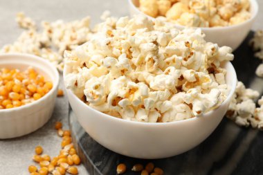 Açık gri masada patlamış mısır ve mısır taneleri, yakın plan.