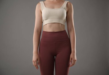 Gri arka planda iyi duruşu olan kadın, yakın plan.