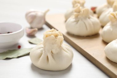 Pişmemiş khinkaliler (hamur tatlısı) ve beyaz ahşap masa üzerindeki baharatlar, yakın plan.