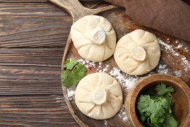 Ahşap masada pişmemiş khinkaliler (hamur tatlısı) ve maydanoz, üst manzara. Metin için boşluk